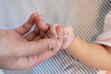 Asian parent hands holding newborn baby fingers, Closeup mother’s hand holding their new born baby day. Together love harmony peace family nursery healthcare.