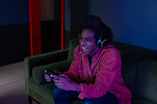 Mid adult male gamer playing at home at night