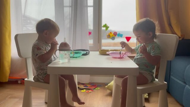 baby group eating at the table in kindergarten. happy family kid dream concept. baby twins learning to eat sitting at the table near the window eating. baby lifestyle group kindergarten breakfast