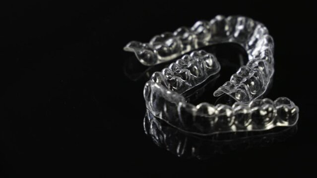 Invisible orthodontics cosmetic brackets on black background. Tooth aligners, for beautiful smile.