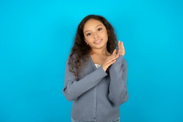 Beautiful teen girl wearing blue jacket over blue background clapping and applauding happy and...