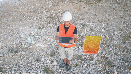 Engineer working on his tablet with digital HUD data hologram display. Graphic