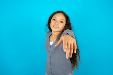 Beautiful teen girl wearing blue jacket over blue background  pointing at camera with a satisfied,...