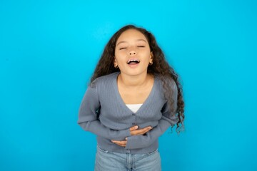 Beautiful teen girl wearing blue jacket over blue background smiling and laughing hard out loud...
