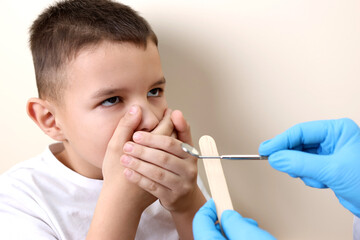 The boy covers his mouth with his hands to protect himself from the examination of the teeth of the oral cavity. Healthcare and dental care concept.
