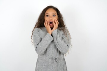 Scared terrified Beautiful teen girl wearing  grey dress over white background shocked with prices...