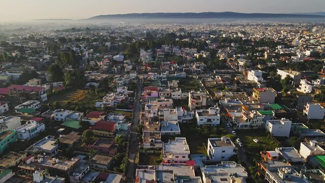 An aerial view of Dehradun, an Indian city during sunrise or sunset, with cloudy weather and rows of residential houses.