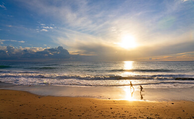Fototapeta na wymiar Beautiful summer seascape at sunset with children running along the beach.