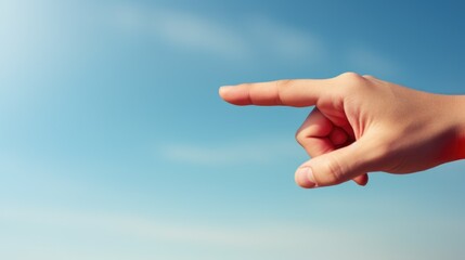 Human hand pointing to the side direction against blue sky