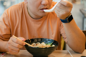 Asian men enjoy eating ramen noodles in japanese restaurant