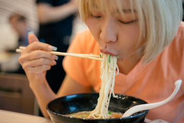 Asian women enjoy eating ramen noodles in japanese restaurant