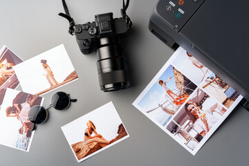 Photo camera with colorful printer photos on gray desk