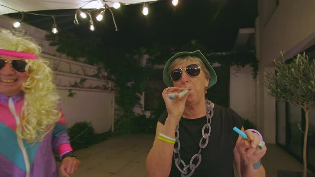 senior woman making noise at funny party using horn noisemaker blower