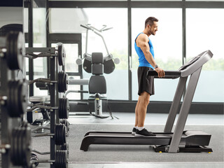 Fototapeta premium Young man standing on a treadmill at a fitness center