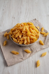 Raw Organic Dry Pennoni Pasta in a Bowl, side view.