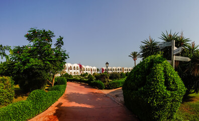 Obraz premium paths to white houses through a green garden in a resort from egypt panorama view