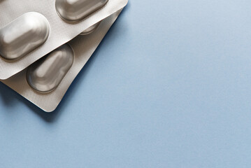 Medicine blister strip on a plain blue background. Pharmacy products. Medicine pills. - obrazy, fototapety, plakaty