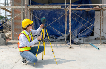 A construction worker is using a laser gauge  to capture the setting of masonry, plastering and...