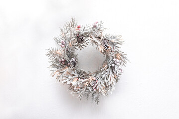 An elegant white Christmas wreath adorning a pristine white wall. Perfect for festive banners and holiday-themed decor.