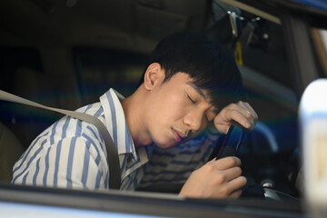 Tired man falls asleep on steering wheel. Unsafe driving from fatigue and drowsiness of the driver.