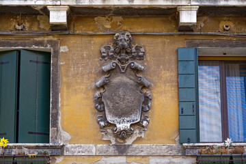 Close-up of weathered yellow facade with lion's head decoration at the old town of Venice on a sunny summer day. Photo taken August 6th, 2023, Venice, Italy.