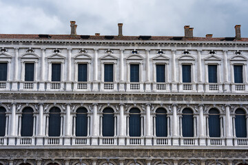 Fototapeta na wymiar Close-up of white stone facade of historic building at Piazza San Marco square at City of Venice on a blue cloudy summer day. Photo taken August 6th, 2023, Venice, Italy.