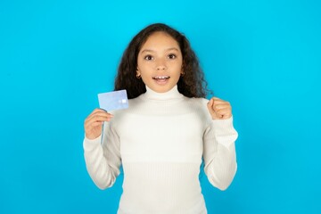Photo of lucky impressed Young beautiful teen girl arm fist holding credit card. Celebrated - obrazy, fototapety, plakaty