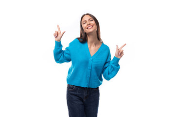 young charming brunette lady dressed in a blue V-neck sweater actively jests on a white background...