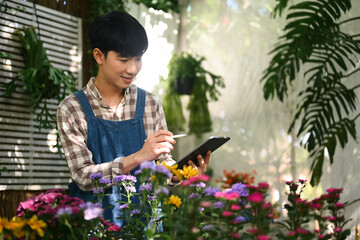 Pleased male florist checking, receiving online order on digital tablet. Floristry, business and...