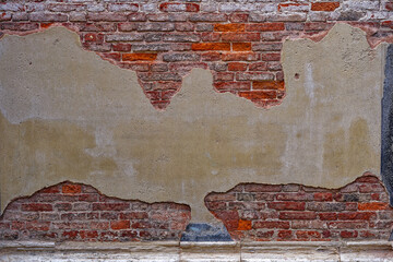 Close-up of brick wall with damaged plaster at City of Venice on a cloudy summer day. Photo taken August 6th, 2023, Venice, Italy.