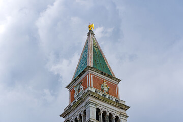 Piazza San Marco with top of Campanile di San Marco with golden angel on top at City of Venice on a cloudy summer day. Photo taken August 6th, 2023, Venice, Italy.