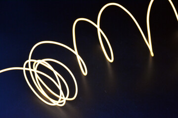 A glowing chaos of thin glowing wires. An unusual, unique glowing background of chaotically stacked thin wires, orange, yellow, red glowing harness, illuminated, thin wire placed on a thin background.