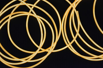 A glowing chaos of thin glowing wires. An unusual, unique glowing background of chaotically stacked thin wires, orange, yellow, red glowing harness, illuminated, thin wire placed on a thin background.