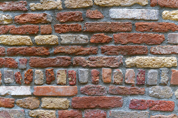 Close-up of weathered red and yellow brick wall at the old town of Venice on a sunny summer day. Photo taken August 6th, 2023, Venice, Italy.