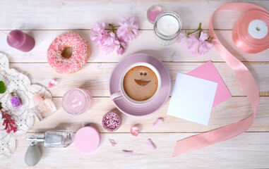 Coffee cup, donut, sakura flowers, aromatic candles, romantic little things on white wooden table, concept of Relaxation Haven in boudoir, female life