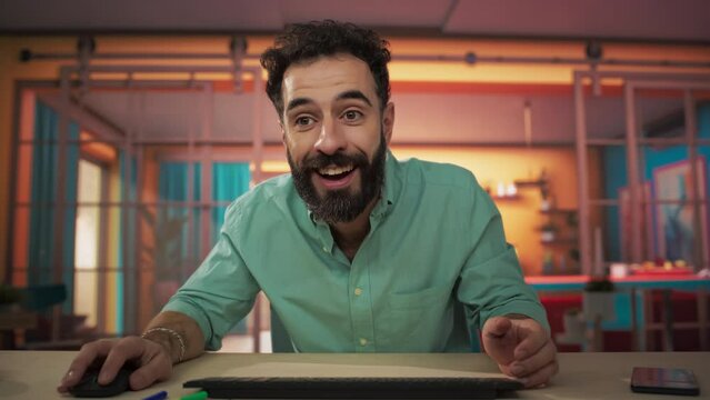 Screen POV: Handsome Man Sitting at a Table in a Cozy Colorful Apartment and Using Computer. Male Adult Smiling and Chatting on Social Media, Doing Online Shopping, Checking Happy News. . Slow Motion