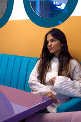 Mujer Joven latina  de cabello castaño largo sentada en cafe