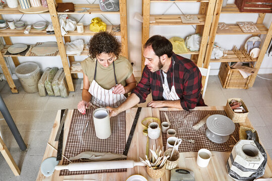 An experienced artisan guides an apprentice in ceramic techniques, sharing knowledge in his workshop. School of craftsmanship
