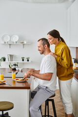 side view of smiling man enjoying tasty breakfast near caring wife in kitchen, child-free couple