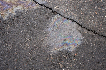Obraz premium Leakage of oil or gasoline from the car on the asphalt in the parking lot. The concept of environmental pollution.