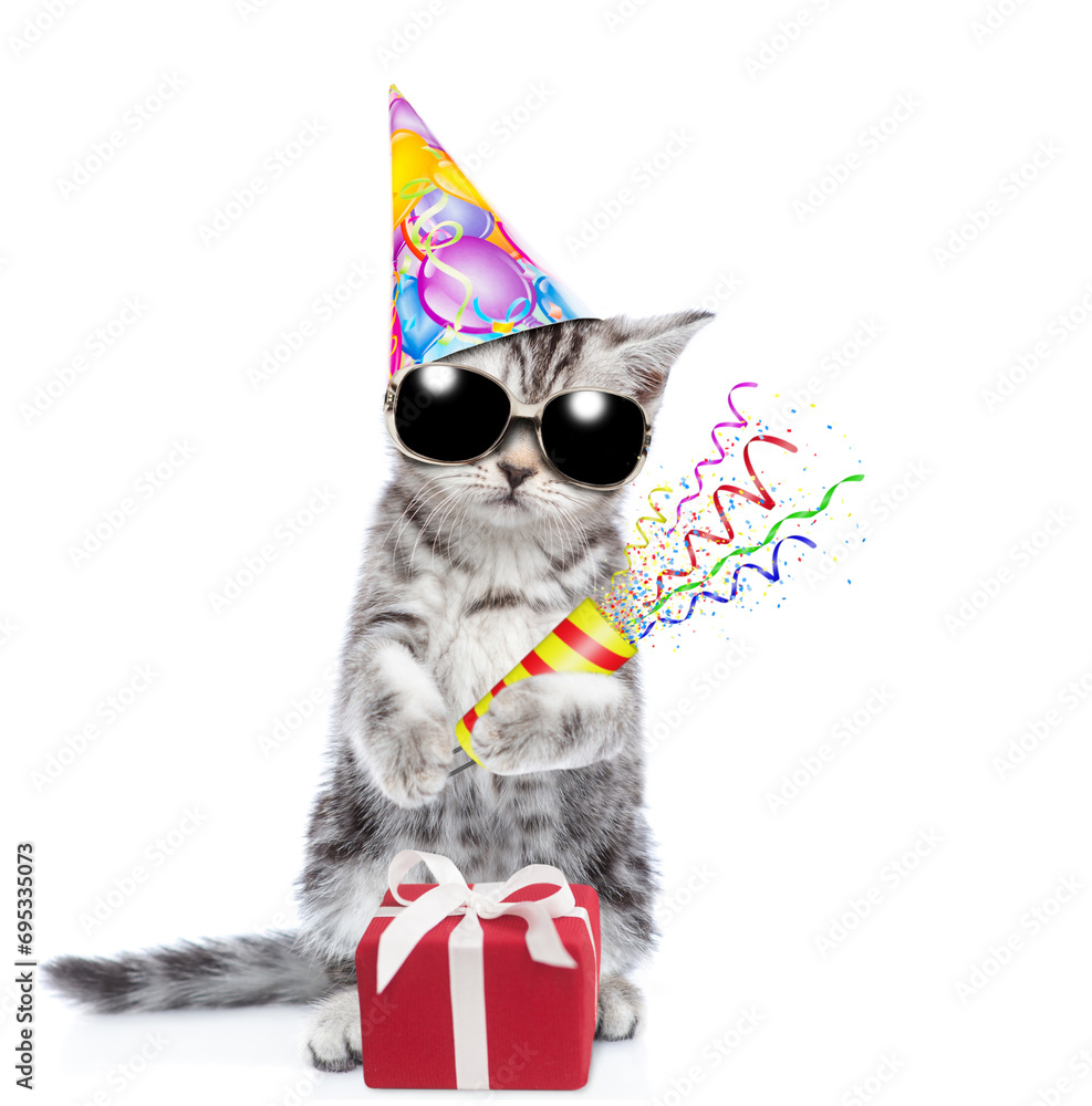 Aufkleber Funny kitten wearing sunglasses and party cap holds exploding firecracker. Isolated on blue background