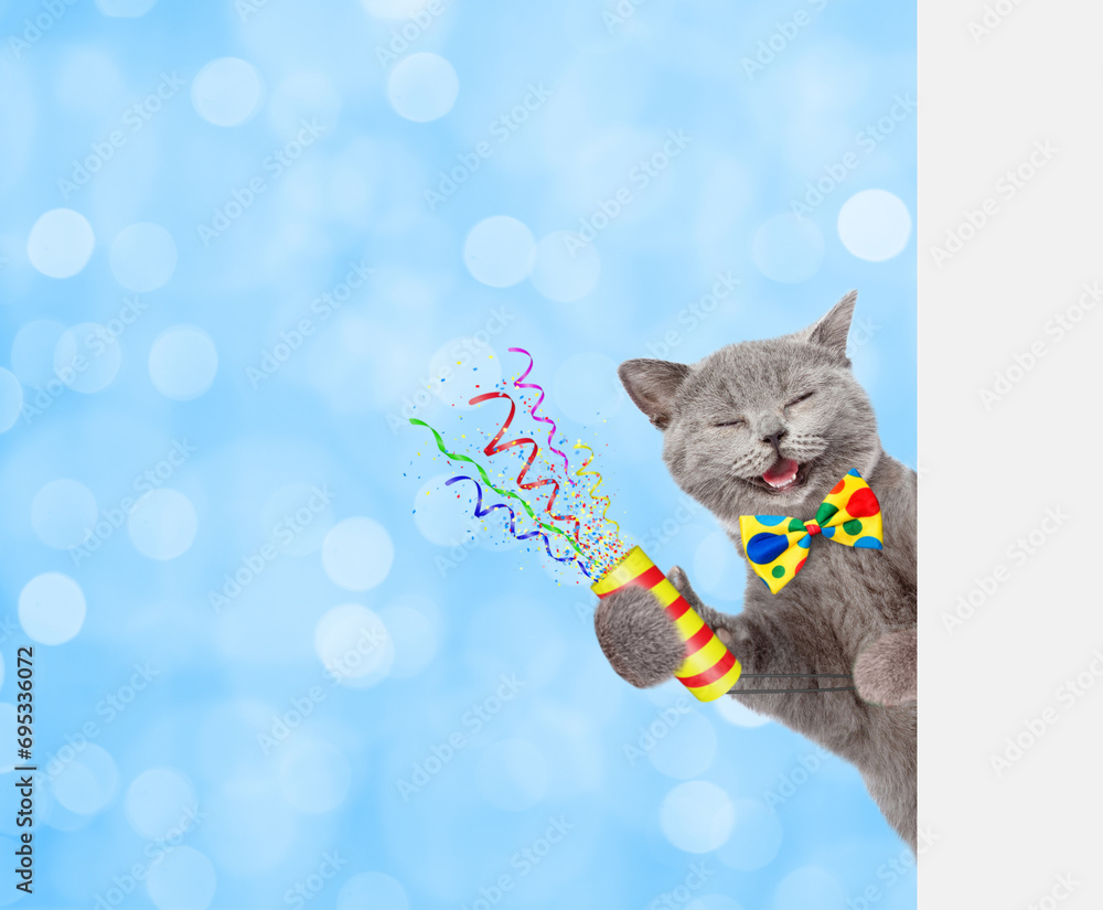 Aufkleber Happy cat wearing tie bow holds exploding firecracker and looks from behind empty white banner. festive blue blured background