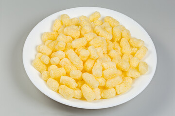 Sweet corn puffs on a white plate on gray background