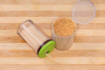 Bamboo toothpicks in two different plastic containers on wooden surface