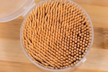 Wooden bamboo toothpicks in open plastic container, fragment top view