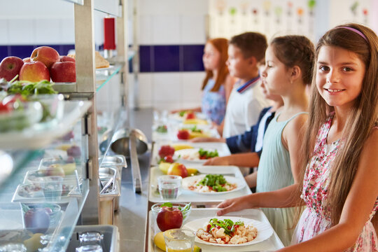 Smiling girl with friends and food trays standing in line