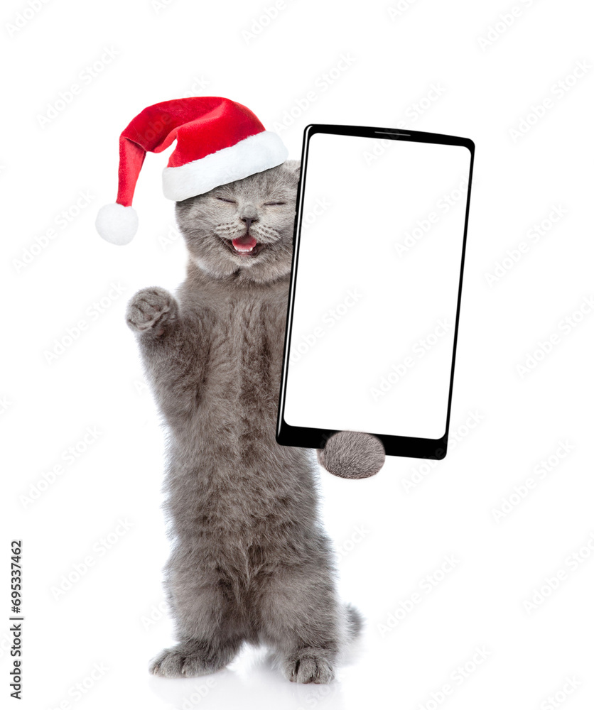 Poster cute kitten wearing santa hat holds smartphone with white blank screen in it paw. empty free space f