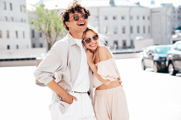 Obraz premium Young smiling beautiful woman and her handsome boyfriend in casual summer clothes. Happy cheerful family. Female having fun. Couple posing in the street background at sunny day. In sunglasses
