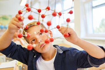 Schoolkid analyzing molecular structure in class - Powered by Adobe