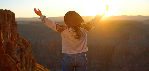 A free-spirited cowgirl stands proudly at the edge of the grand canyon, her jeans blending with the...